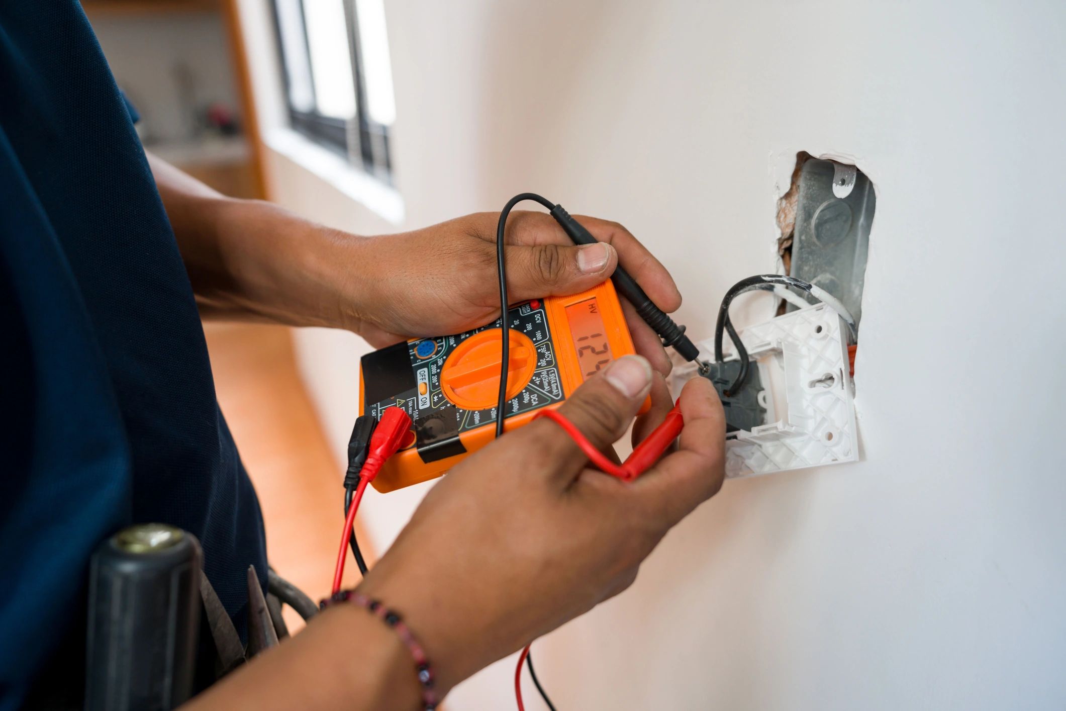 Electrician testing an electrical outlet with a multimeter